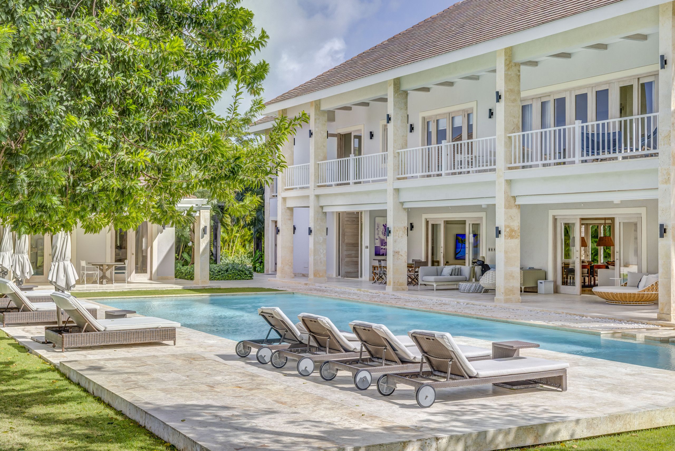 A pool area with lounge chairs, a covered patio, and a two-story building with balconies.