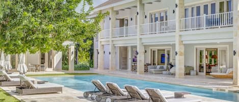 A pool area with lounge chairs, a covered patio, and a two-story building with balconies.
