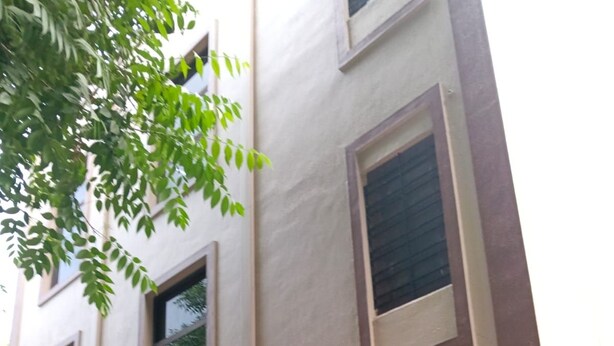 A building with a garage entrance, a motorcycle parked inside, and a staircase leading to an upper level.