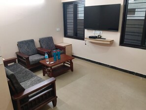 Una sala de estar con un conjunto de sofá, una mesa de centro y un televisor de pantalla plana montado en la pared.
