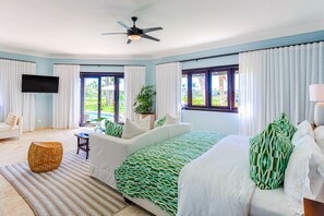 Un dormitorio con cama, sofá, televisión y vistas al exterior.