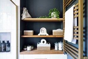 A bathroom shelf with toiletries, a clock, and a towel rack. - Elegant St Johns Wood Mews-King Bed & Workspace (London)