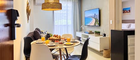 Una habitación de hotel moderna con comedor, televisión y kitchenette.