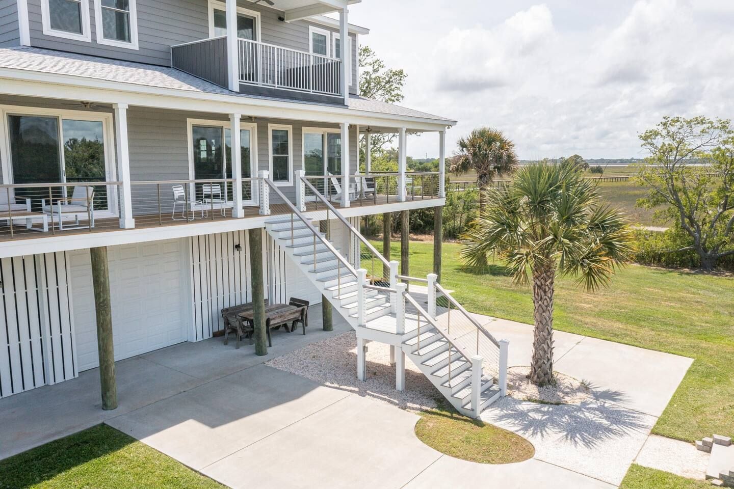 A two-story house with a covered patio, outdoor seating, and a staircase leading to a balcony.