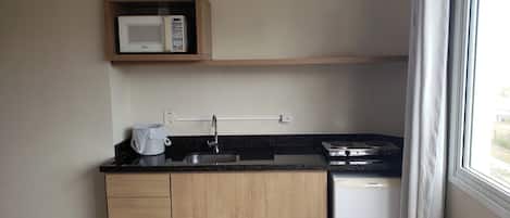 A compact kitchen with a microwave, stove, and sink.