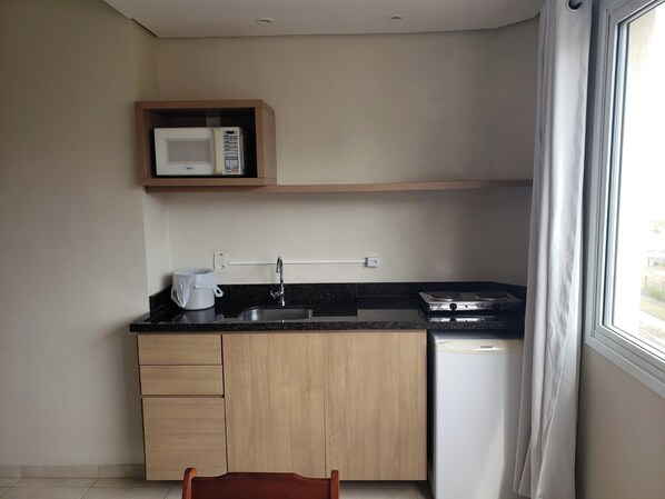 A compact kitchen with a microwave, stove, and sink.