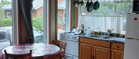 A kitchen with a round table, wooden chairs, a stove, and cabinets.