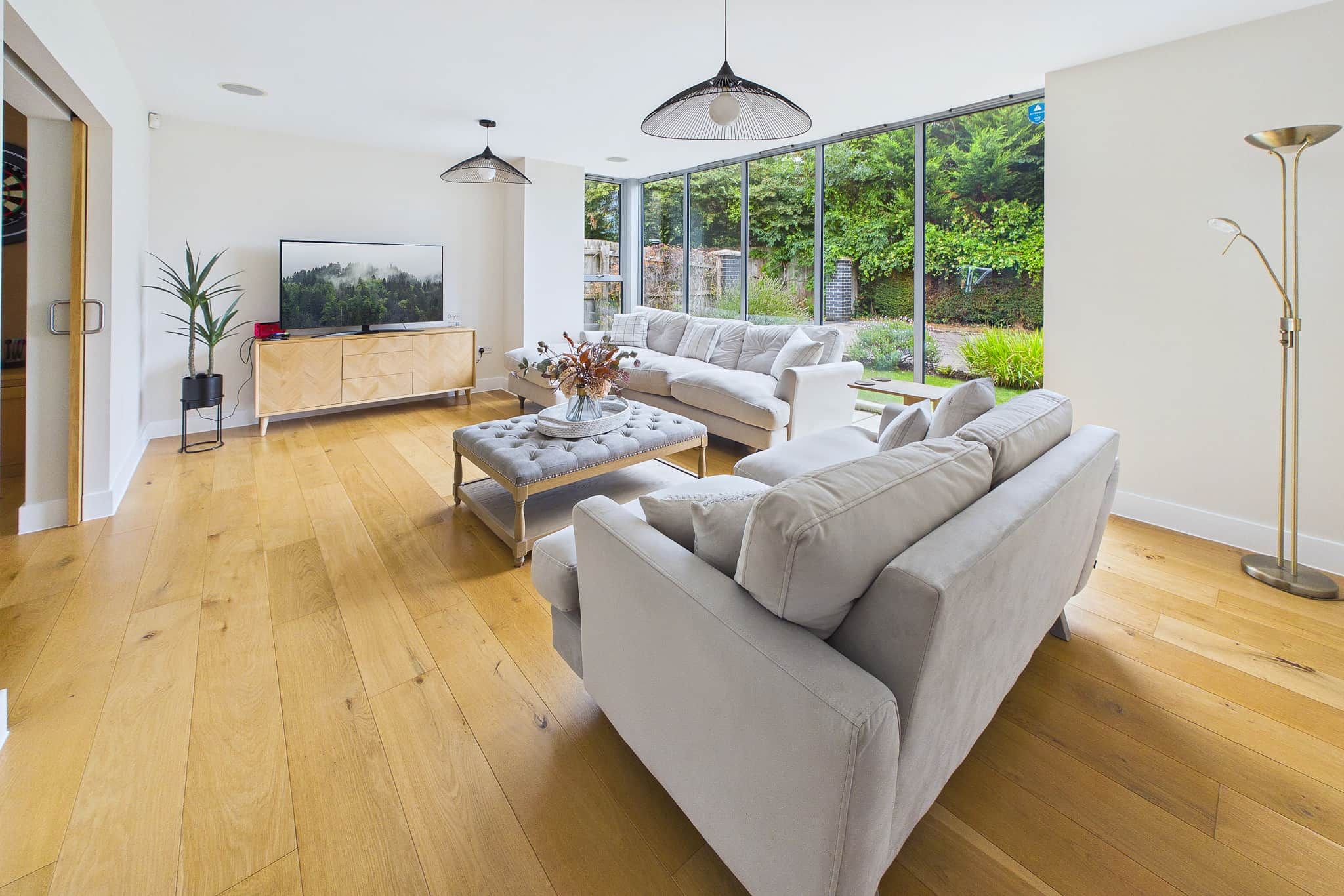 Un salon moderne avec un canapé gris, une table basse et un téléviseur posé sur un meuble en bois.