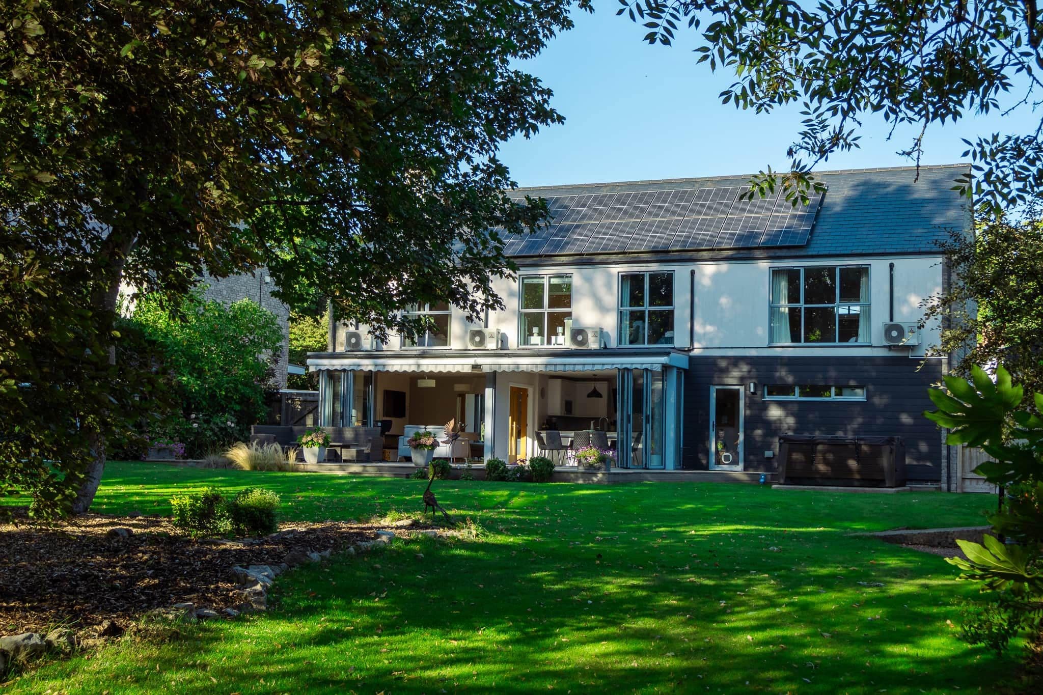 A two-story house with a covered patio, a lawn, and a small garden area.