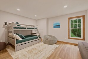 A bunk bed with a ladder, a round ottoman, a painting, and a window with a view of trees. - NEW! Hideaway at Pinnacle in Boone, NC (Boone)