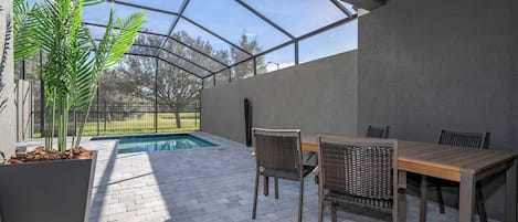 Un espacio al aire libre techado con piscina, mobiliario y vistas del paisaje circundante.