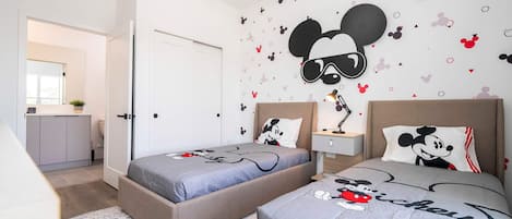 A bedroom with two beds, each with Mickey Mouse-themed bedding.