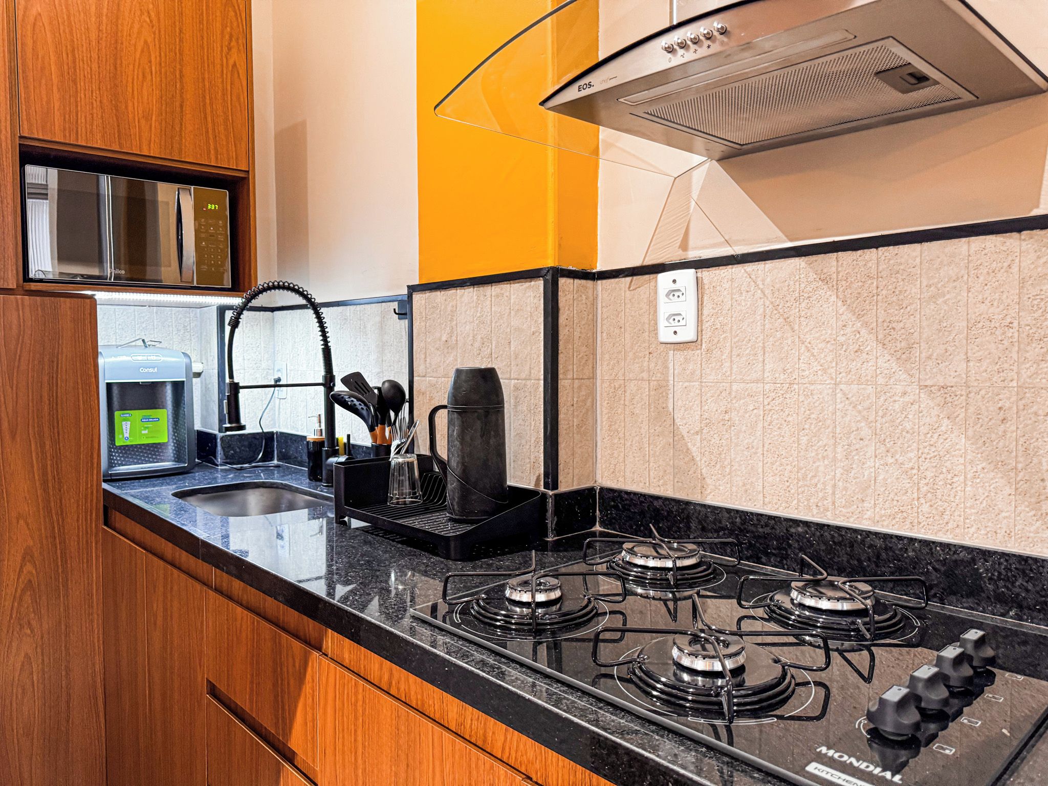 A modern kitchen with a gas stove, a coffee maker, and a water dispenser.