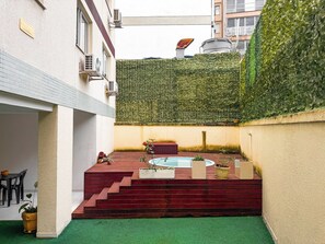 Un pati amb una piscina petita, escales cap a una zona d'estar i una paret coberta de verdura.