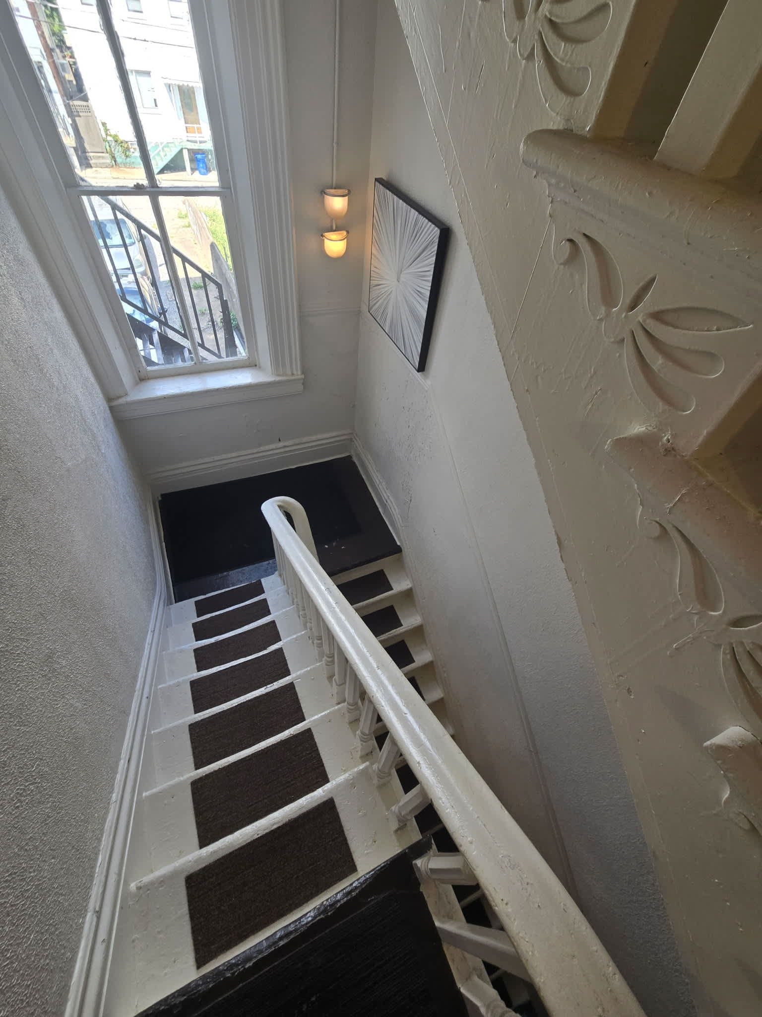 A staircase with white handrails and a black carpeted landing.