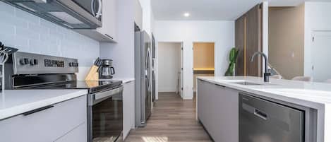 Una cocina moderna con electrodomésticos de acero inoxidable, una isla central y vista al área de comedor.