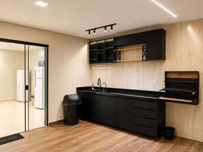 A modern kitchen with black cabinetry, a black countertop, and a built-in wine rack.