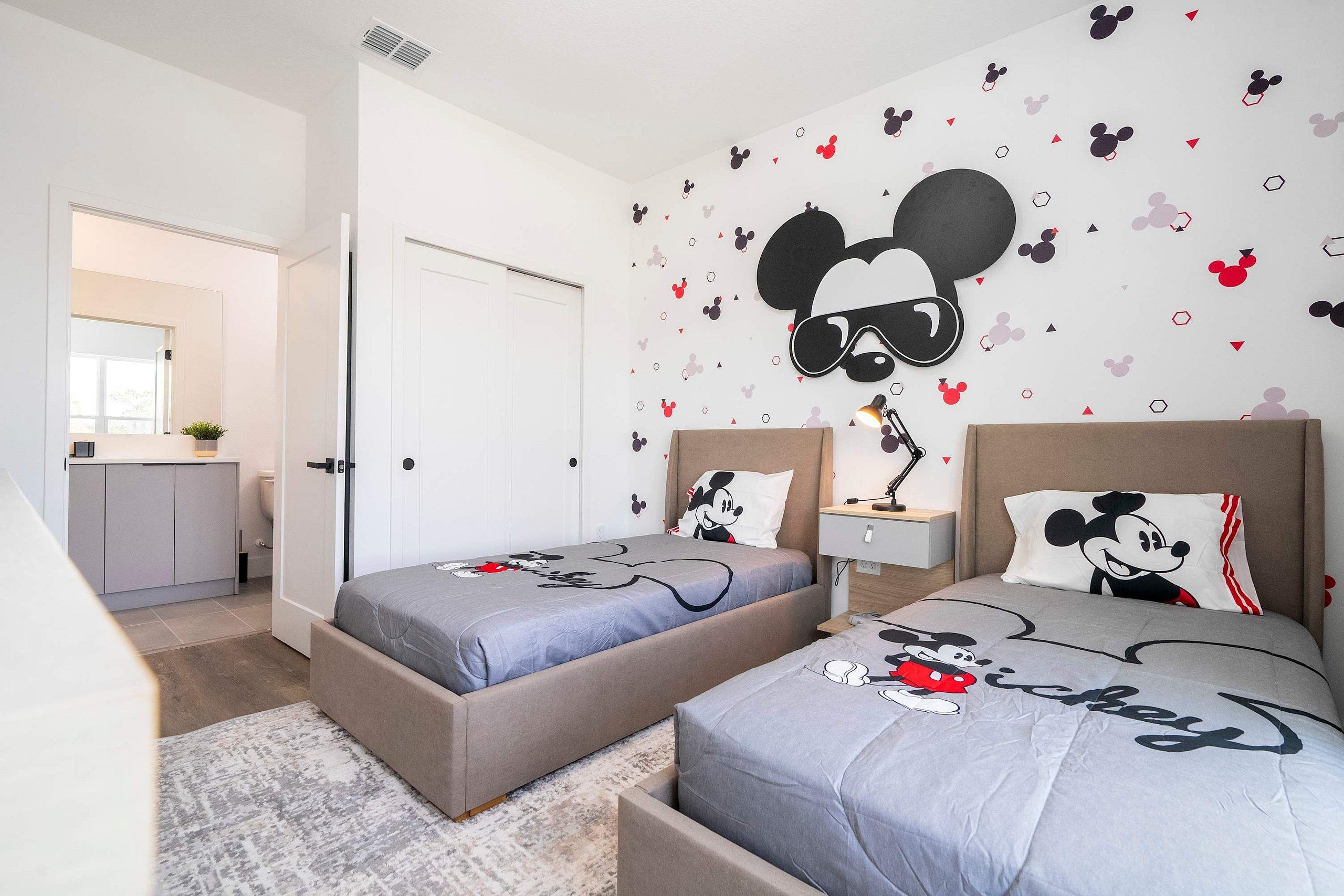 A bedroom with two beds, each with Mickey Mouse-themed bedding.