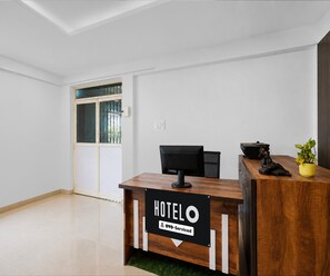 A hotel reception desk with a sign indicating it is serviced by OYO. - Deluxe Room Hotel Naina Luxury Rooms (Hyderabad)