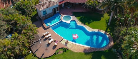 An aerial view of a residential property with a swimming pool, lounge chairs, and a hot tub.