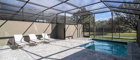 Ein Außenpoolbereich mit Glasveranda, Liegestühlen und Blick auf die umliegende Landschaft.