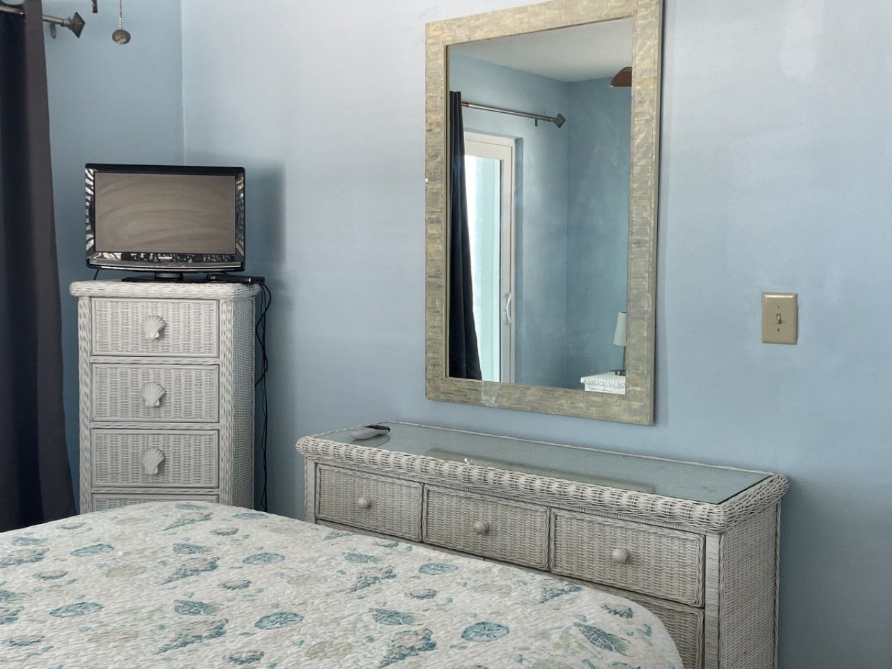 A bedroom with a bed, dresser, mirror, and a television on the dresser.