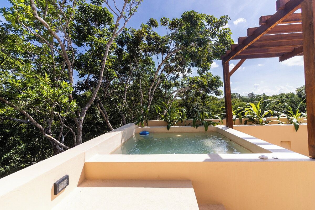 A swimming pool with a wooden pergola structure, surrounded by lush greenery.