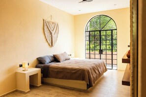 Ein Schlafzimmer mit Bett, Nachttisch und einem großen Bogenfenster.