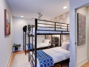 A bunk bed room with a ceiling fan, a small plant, and a patterned wall. - Skyline Stunner | 4BR • 11 Beds • 2 Miles to DT! (Nashville)