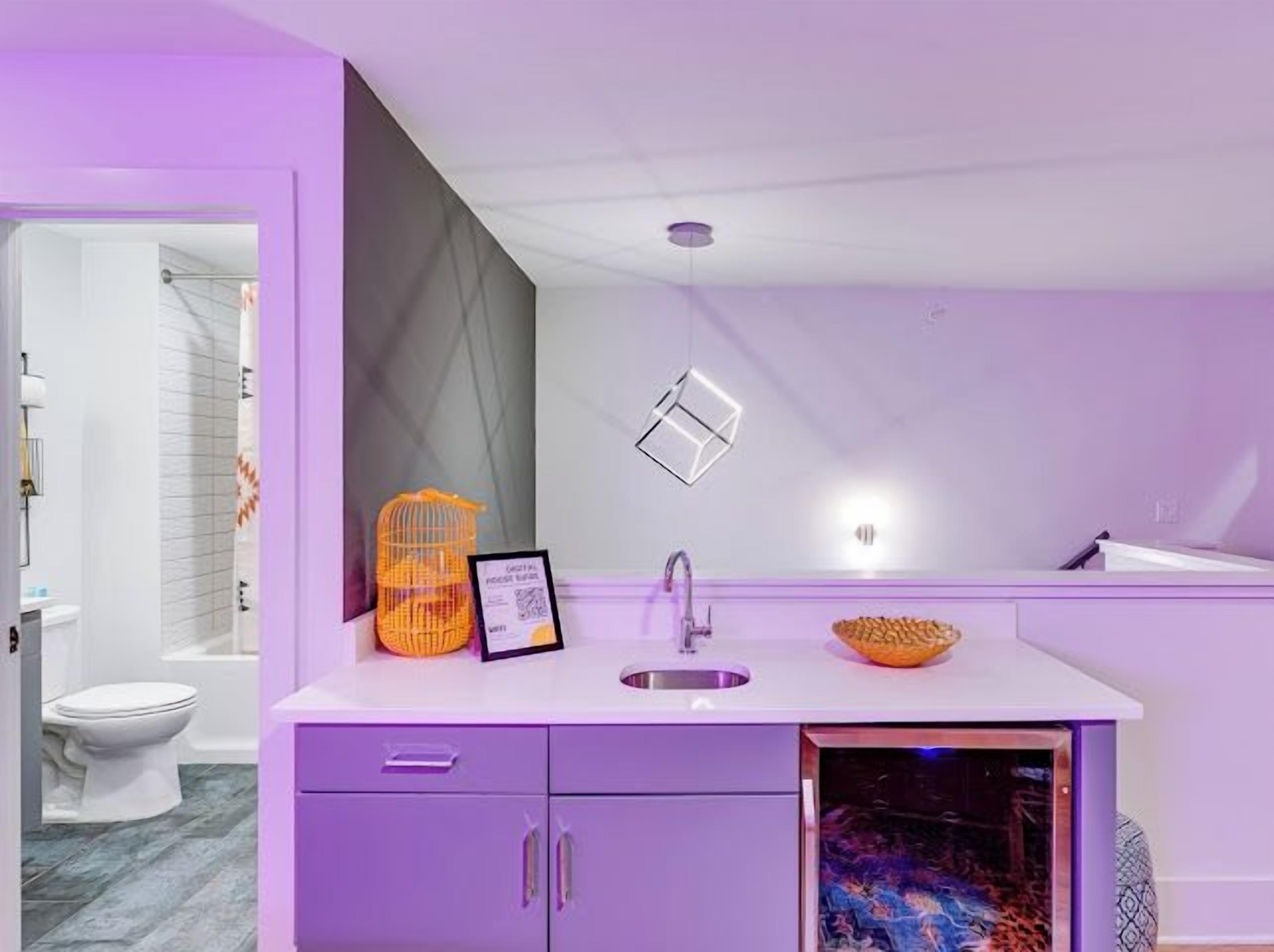Ein modernes Badezimmer mit einem violetten Waschtisch, einem Waschbecken und einer Duschkabine.