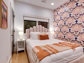 A bedroom with a bed, nightstands, a window, and a patterned wall. - Skyline Stunner | 4BR • 11 Beds • 2 Miles to DT! (Nashville)