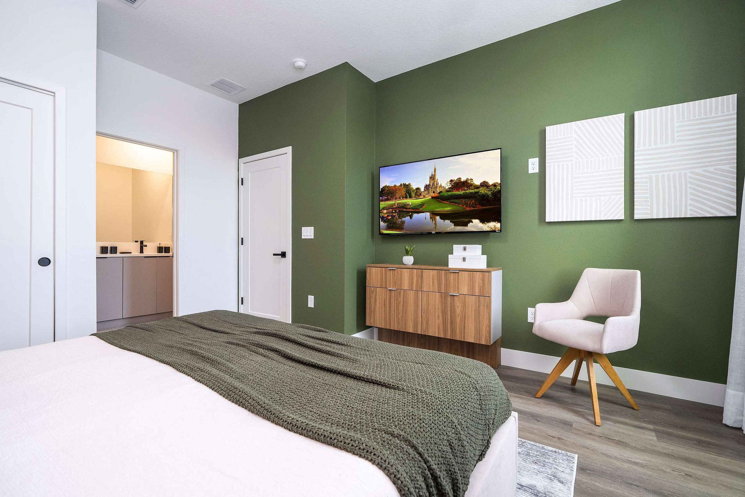 A modern bedroom with a bed, a TV, a wardrobe, and a chair.