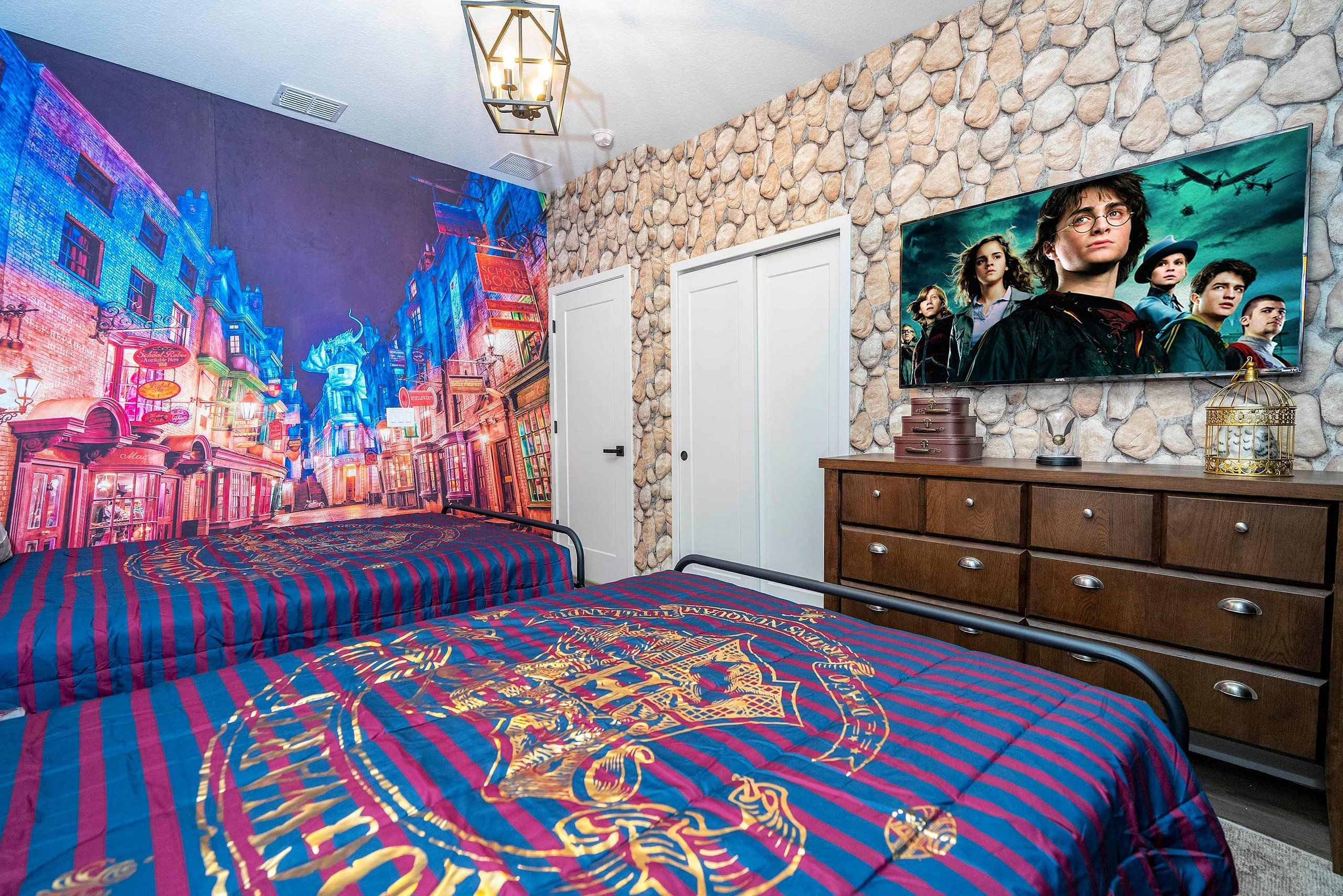 A bedroom with a mural of a cityscape, a bed with a patterned bedspread, a dresser with a television, and a stone wall.