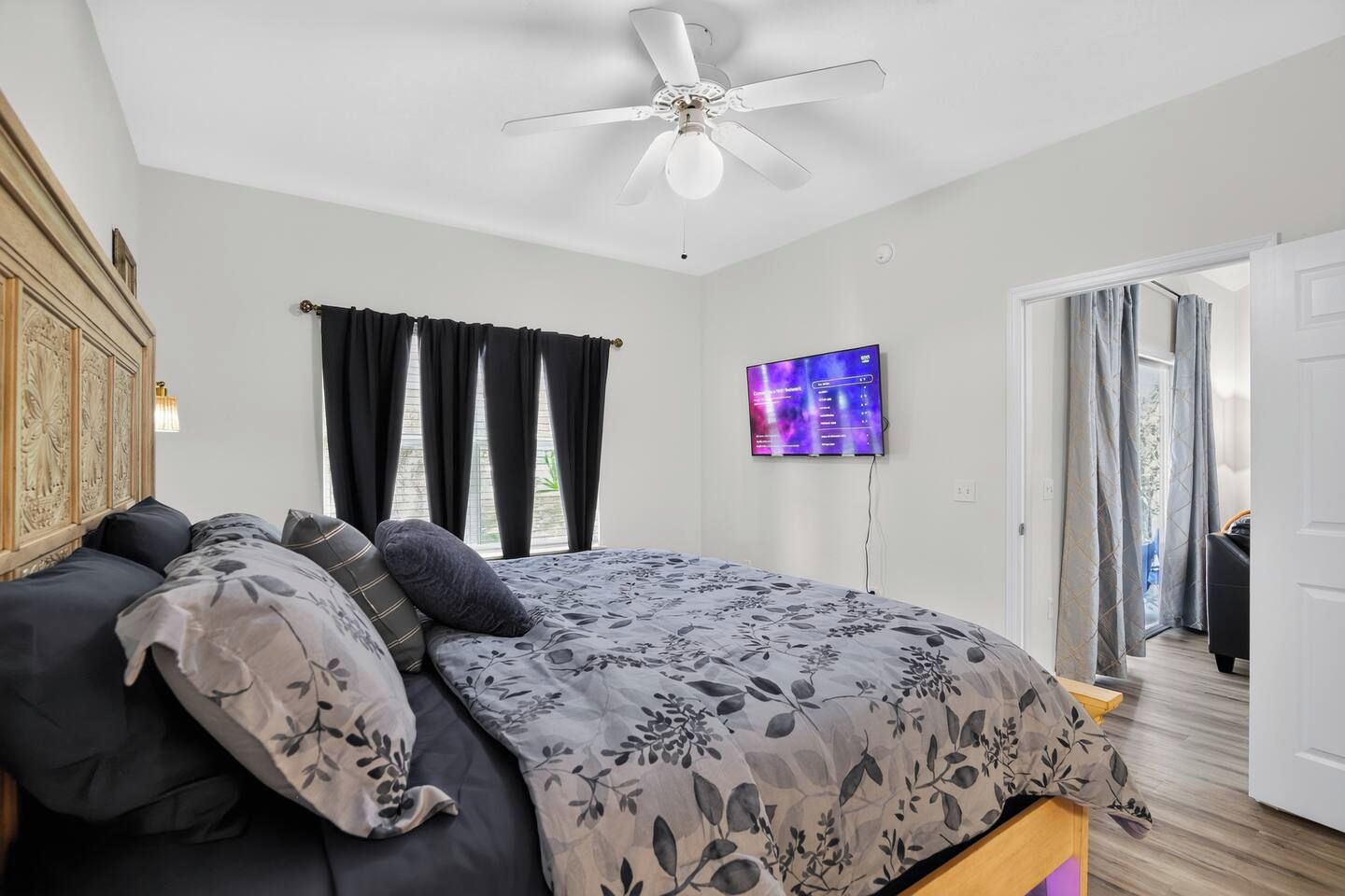 Ein Schlafzimmer mit einem Bett, einem Deckenventilator, einem Fernseher und Blick ins Freie.