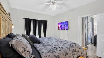Ein Schlafzimmer mit einem Bett, einem Deckenventilator, einem Fernseher und Blick ins Freie.