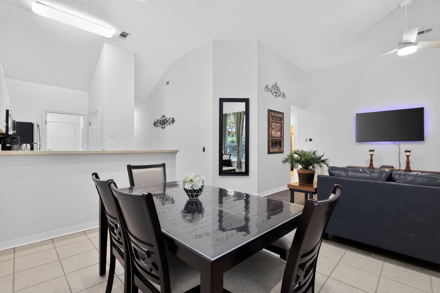 A modern dining area with a glass table, black chairs, and a decorative vase.
