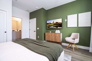 A modern bedroom with a bed, a TV, a wardrobe, and a chair. - Modern 4BR Home Near Disney Private Pool (Davenport)