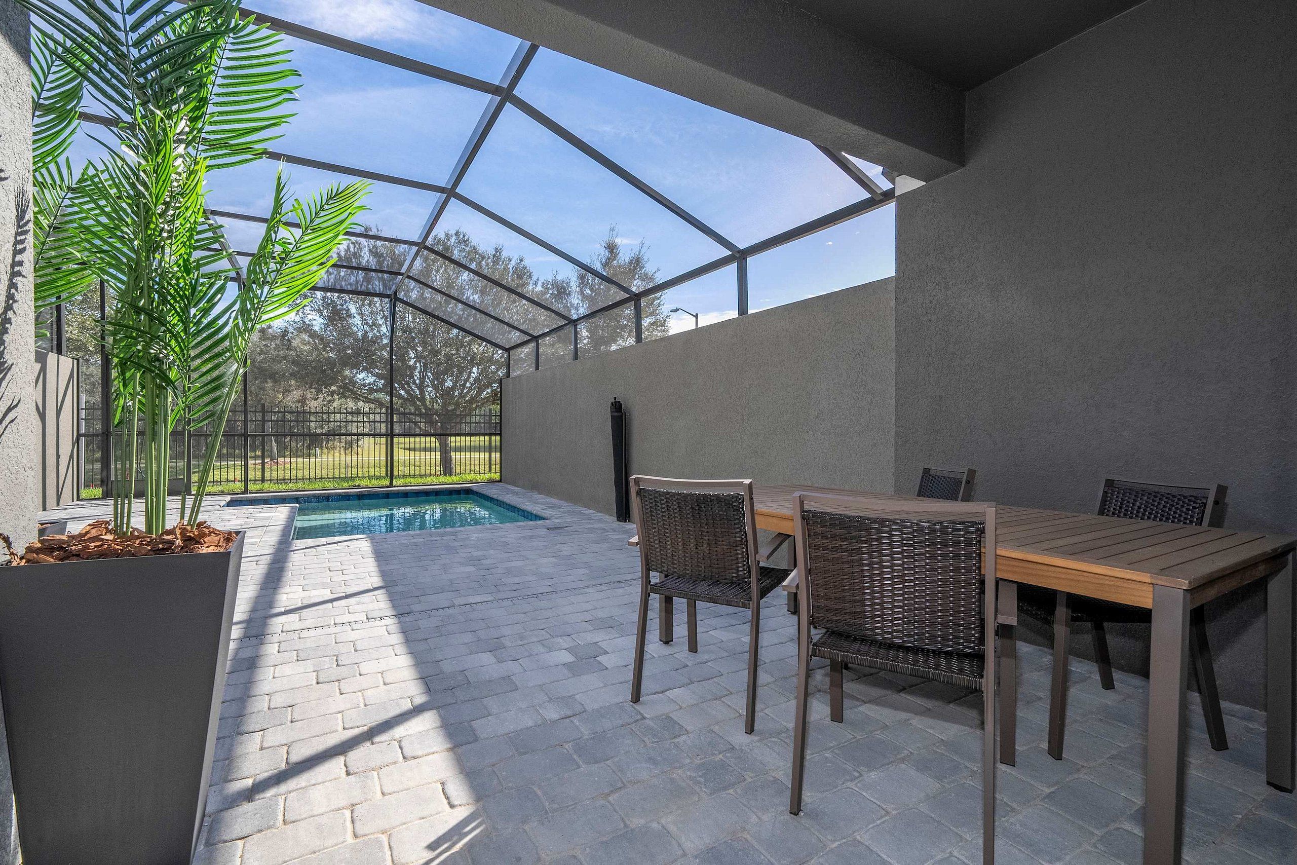 A covered outdoor area with a pool, seating, and a view of the surrounding landscape.
