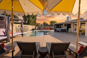Ein Poolbereich mit Liegestühlen und Sonnenschirmen, einem Whirlpool und einer überdachten Sitzgelegenheit.