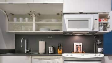 Cozinha compacta com micro-ondas, torradeira e máquina de café.
