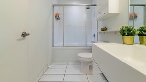 A modern bathroom with a toilet, shower, and sink.