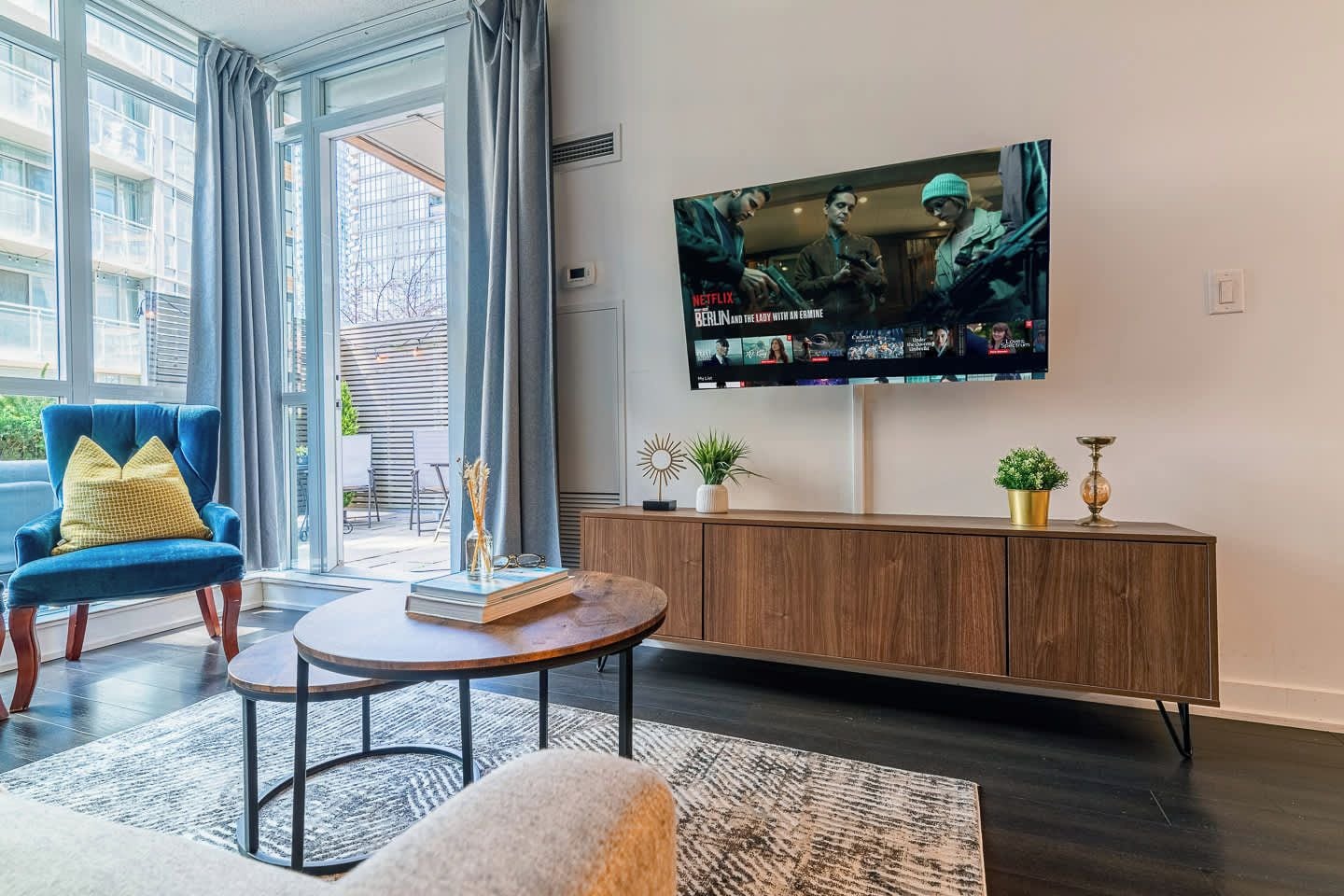A living room with a TV, a blue chair, a round coffee table, and a wooden cabinet.