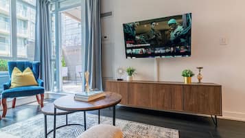 A living room with a TV, a blue chair, a round coffee table, and a wooden cabinet.