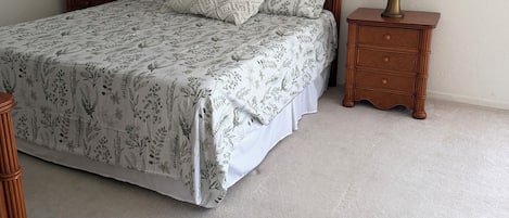 Un dormitorio con cama, dos mesitas de noche, un ventilador de techo y una lámpara de noche.