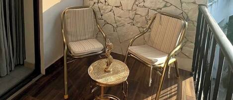 Un balcon avec deux chaises, une table ronde et un mur en pierre.