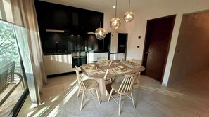 A modern dining area with a round table, chairs, and hanging pendant lights. - 2BR Apartment Prime Location Newly Refurbished (Tulum)