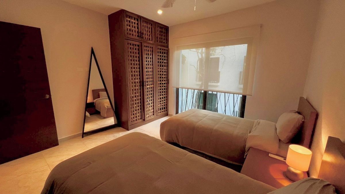 Ein Schlafzimmer mit zwei Betten, einem Holzschrank, einem Spiegel und einem Fenster mit Blick.