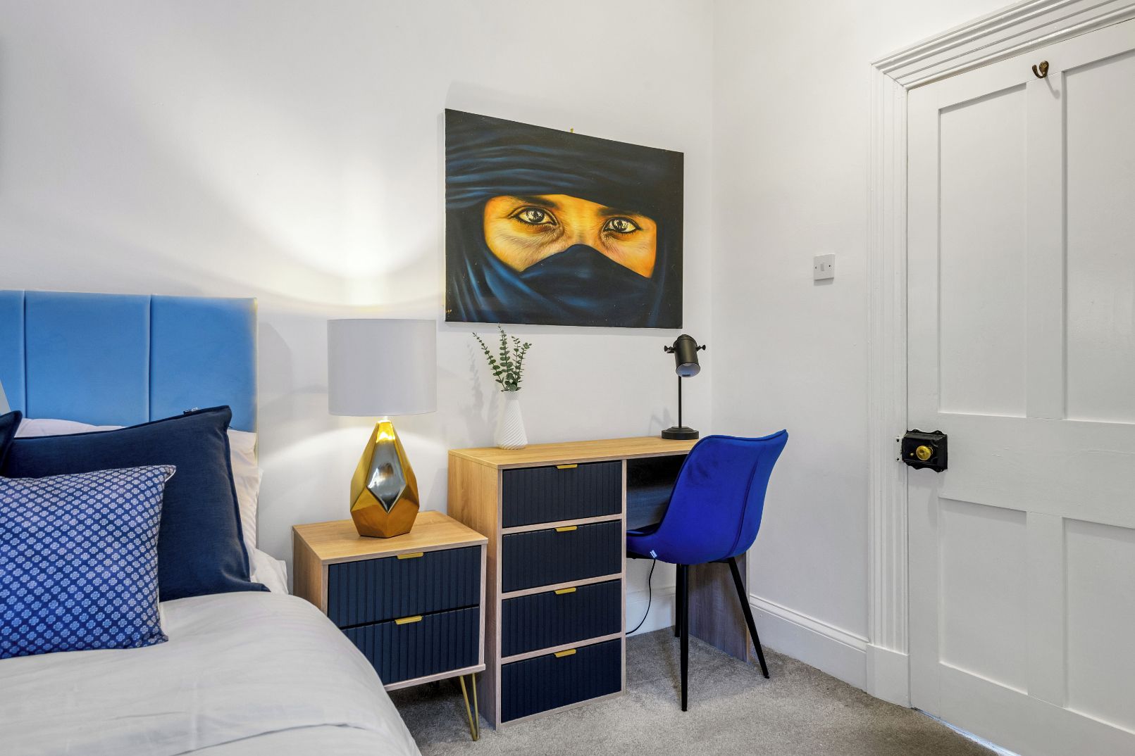 Une chambre à coucher comprenant un lit, un bureau, une chaise, une armoire et une porte.