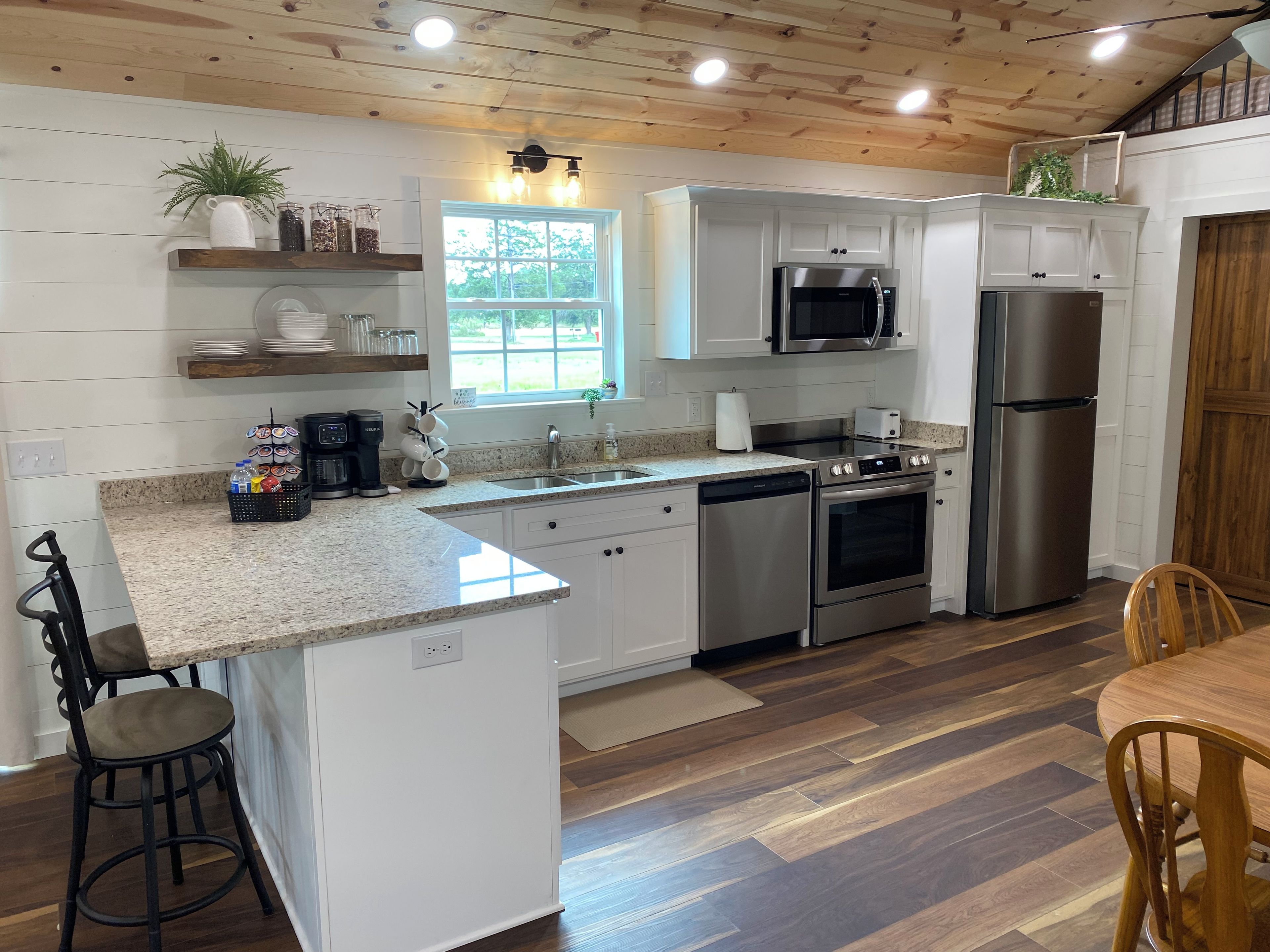 Una cocina moderna con muebles blancos, electrodomésticos de acero inoxidable y techo de madera.