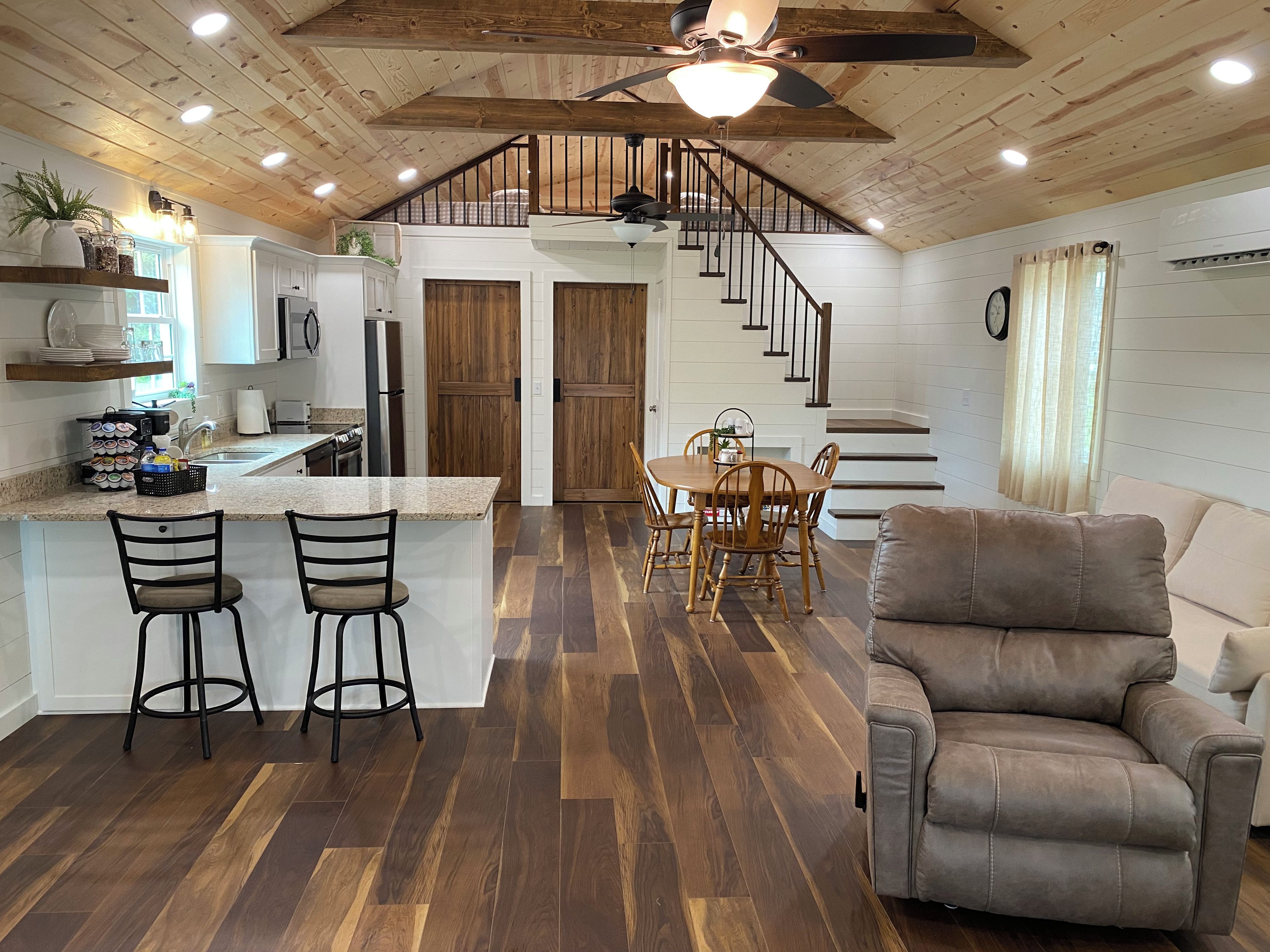 Una cocina amplia con una isla central, suelo de madera y una zona de comedor con mesa y sillas.